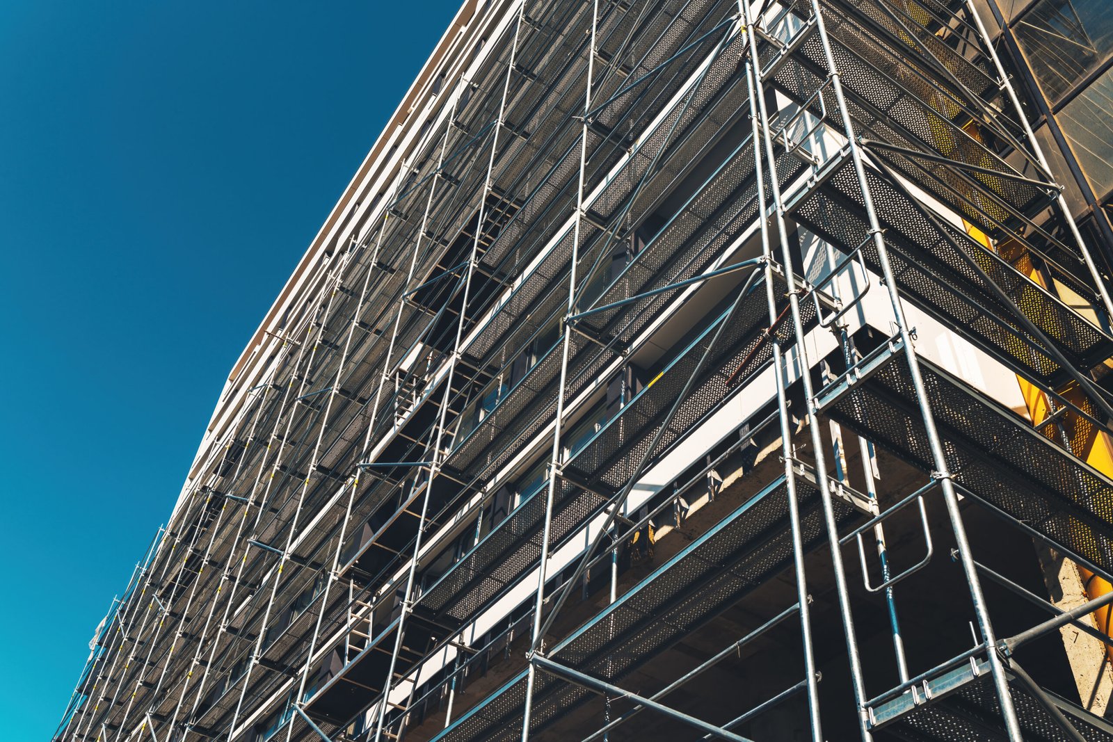 Construction site, scaffolding and building. Real estate development industry concept against blue sky.