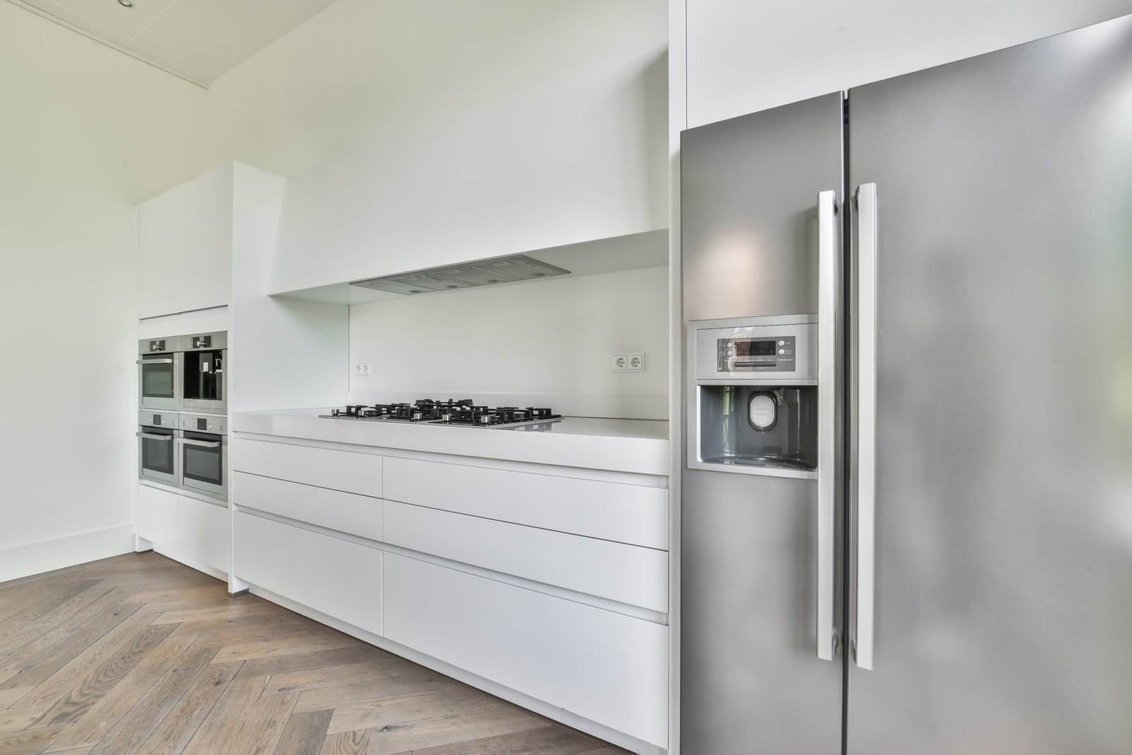 beautiful kitchen in new luxury home with pendant lights, hardwood floors, and stainless steel appliances